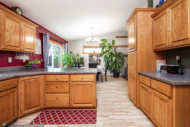 106 12th St NE, Barnesville, MN 56514 - kitchen featuring light wood-style flooring, lofted ceiling, a chandelier, a peninsula, and brown cabinets
