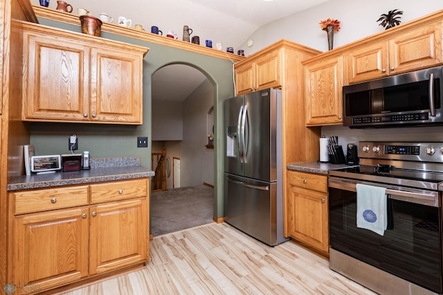 106 12th St NE, Barnesville, MN 56514 - kitchen with stainless steel appliances, light wood-style flooring, dark countertops, arched walkways, and lofted ceiling