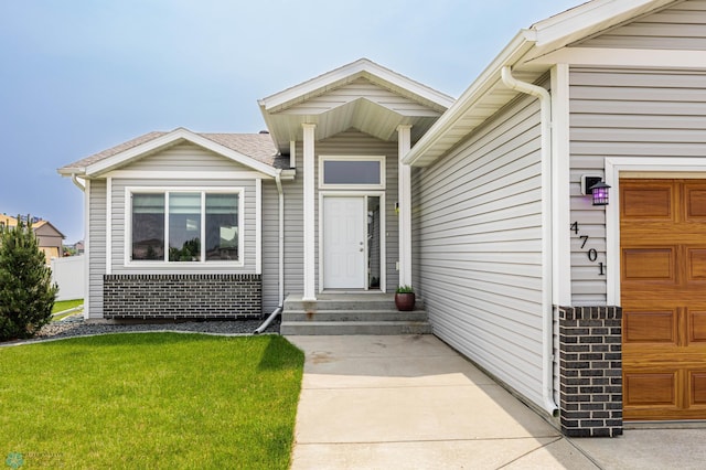 4701 11th St W, West Fargo, ND 58078 - property entrance featuring an attached garage, brick siding, and a lawn
