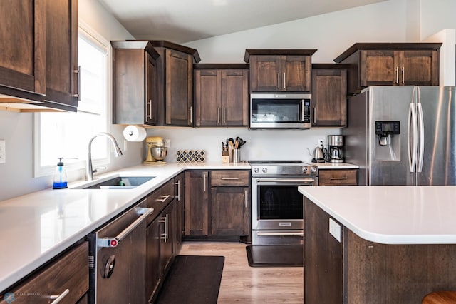 4701 11th St W, West Fargo, ND 58078 - kitchen featuring stainless steel appliances, healthy amount of natural light, light wood-type flooring, dark brown cabinetry, and lofted ceiling
