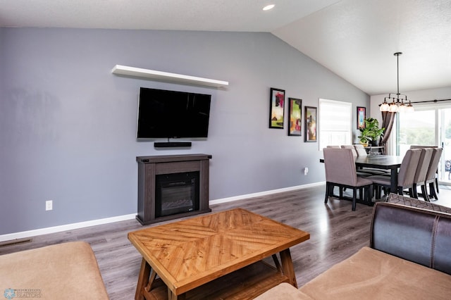 4701 11th St W, West Fargo, ND 58078 - living area featuring lofted ceiling, wood finished floors, a chandelier, and a glass covered fireplace