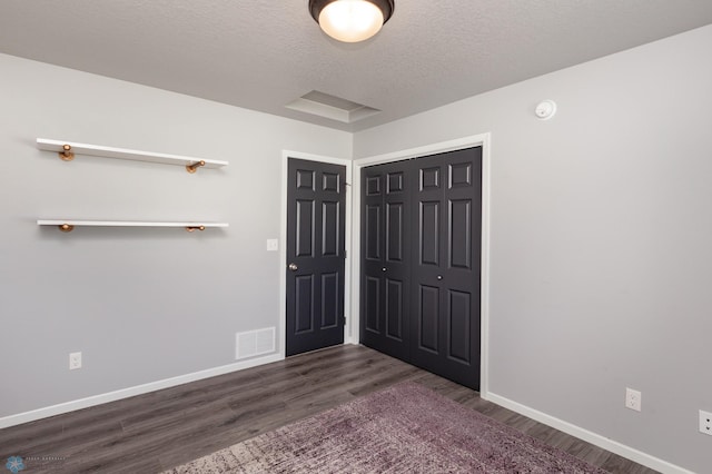 4701 11th St W, West Fargo, ND 58078 - unfurnished bedroom with dark wood-style floors, a closet, and a textured ceiling