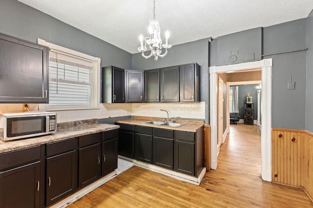 3114 Russell Ave N, Minneapolis, MN 55411 - kitchen featuring stainless steel microwave, light wood finished floors, tasteful backsplash, a chandelier, and decorative light fixtures