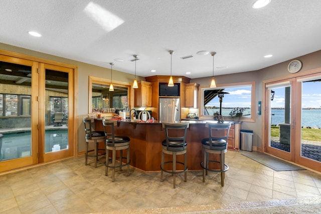 22620 Hayward Ave N, Forest Lake, MN 55025 - kitchen with freestanding refrigerator, brown cabinetry, a kitchen breakfast bar, a peninsula, and a textured ceiling