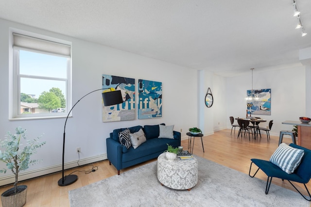 215 7th St NE Unit 205, Minneapolis, MN 55413 - living area featuring a baseboard heating unit, wood finished floors, a chandelier, and track lighting