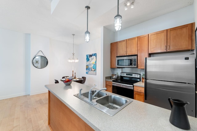 215 7th St NE Unit 205, Minneapolis, MN 55413 - kitchen with appliances with stainless steel finishes, brown cabinets, pendant lighting, light wood-style flooring, and light countertops