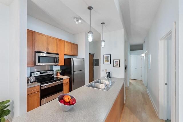 215 7th St NE Unit 205, Minneapolis, MN 55413 - kitchen featuring stainless steel appliances, light wood finished floors, brown cabinets, and pendant lighting
