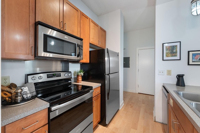 215 7th St NE Unit 205, Minneapolis, MN 55413 - kitchen with appliances with stainless steel finishes, brown cabinets, light wood-type flooring, and light countertops