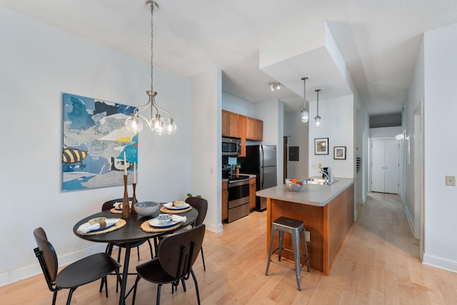 215 7th St NE Unit 205, Minneapolis, MN 55413 - kitchen featuring stainless steel appliances, light wood-type flooring, a kitchen breakfast bar, brown cabinets, and light countertops