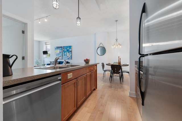215 7th St NE Unit 205, Minneapolis, MN 55413 - kitchen with stainless steel appliances, brown cabinetry, dark countertops, light wood-type flooring, and pendant lighting
