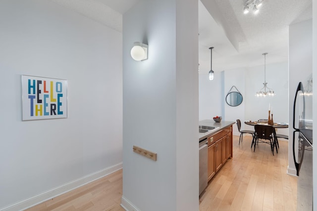 215 7th St NE Unit 205, Minneapolis, MN 55413 - kitchen featuring light wood-type flooring, brown cabinetry, hanging light fixtures, stainless steel dishwasher, and a chandelier