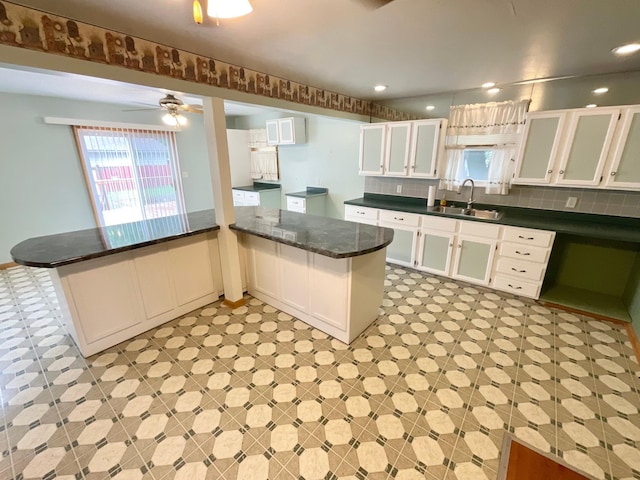 108 Johnson St NE, Brownsdale, MN 55918 - kitchen featuring a peninsula, white cabinetry, glass insert cabinets, backsplash, and a ceiling fan