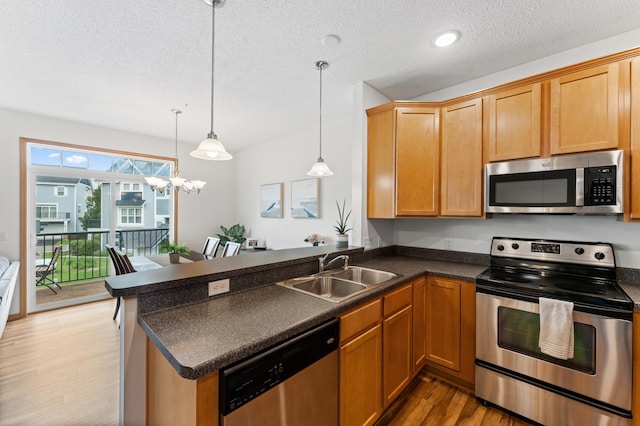 15588 Early Bird Cir Unit 1704, Apple Valley, MN 55124 - kitchen with stainless steel appliances, light wood-style flooring, a textured ceiling, dark countertops, and a peninsula