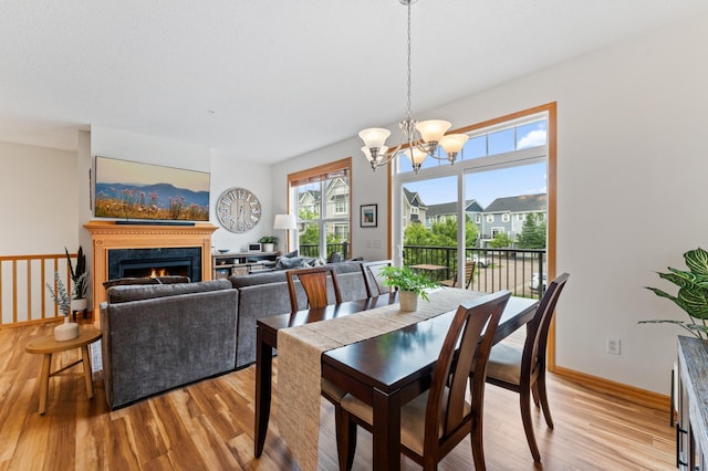 15588 Early Bird Cir Unit 1704, Apple Valley, MN 55124 - dining space featuring light wood-style flooring, a chandelier, and a warm lit fireplace