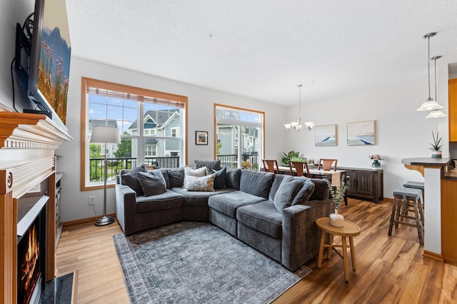 15588 Early Bird Cir Unit 1704, Apple Valley, MN 55124 - living room with a fireplace with flush hearth, light wood finished floors, a chandelier, and a textured ceiling