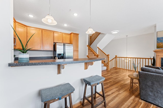 15588 Early Bird Cir Unit 1704, Apple Valley, MN 55124 - kitchen featuring stainless steel fridge with ice dispenser, a breakfast bar area, wood finished floors, a peninsula, and dark countertops