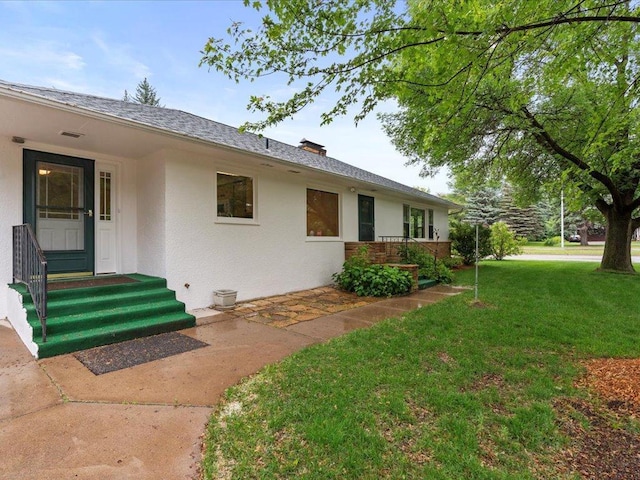517 Cedar St, Brainerd, MN 56401 - view of exterior entry with a yard, stucco siding, and roof with shingles