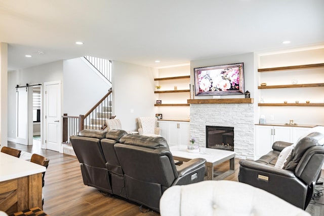 1205 Skyview Cir NW, Rochester, MN 55901 - living room featuring dark wood-type flooring, stairs, a barn door, recessed lighting, and a stone fireplace