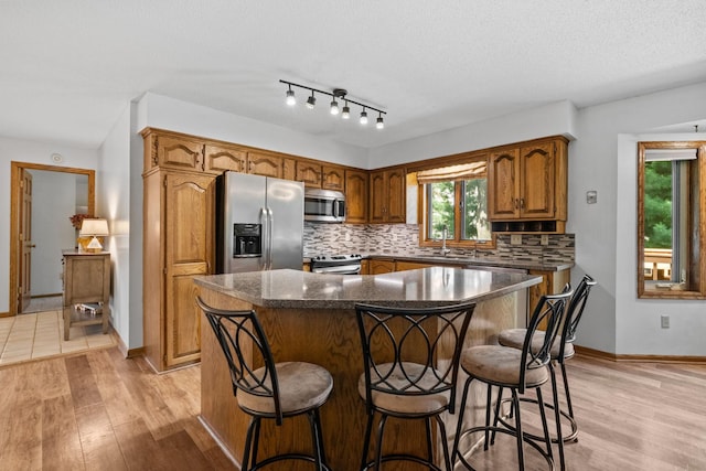 13790 Crane St NW, Andover, MN 55304 - kitchen featuring appliances with stainless steel finishes, tasteful backsplash, light wood-style flooring, and brown cabinets