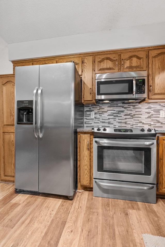 13790 Crane St NW, Andover, MN 55304 - kitchen with stainless steel appliances, brown cabinets, backsplash, light wood-style floors, and a textured ceiling