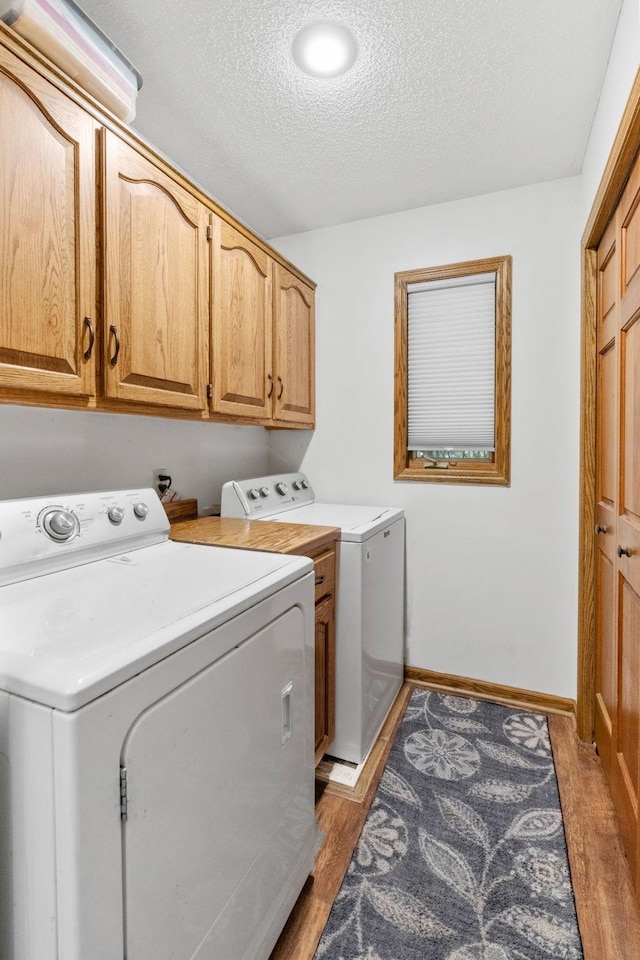 13790 Crane St NW, Andover, MN 55304 - washroom with independent washer and dryer, cabinet space, a textured ceiling, and light wood-style flooring