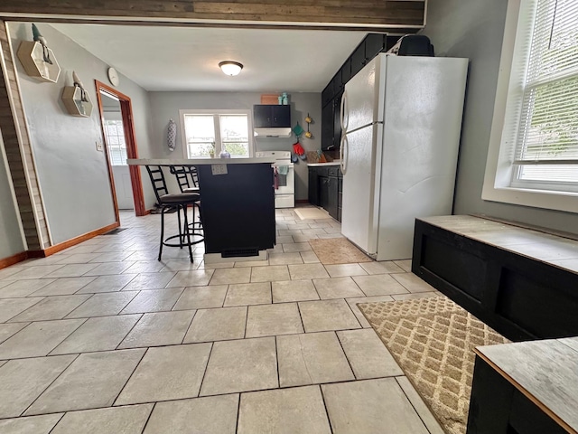 420 7th St, Marshall, MN 56258 - kitchen with white appliances, a kitchen bar, a kitchen island, light countertops, and dark cabinets