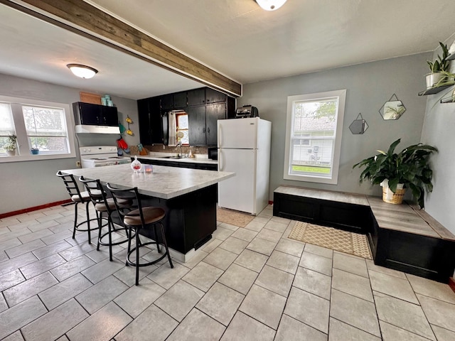 420 7th St, Marshall, MN 56258 - kitchen with white appliances, dark cabinetry, plenty of natural light, light countertops, and beamed ceiling