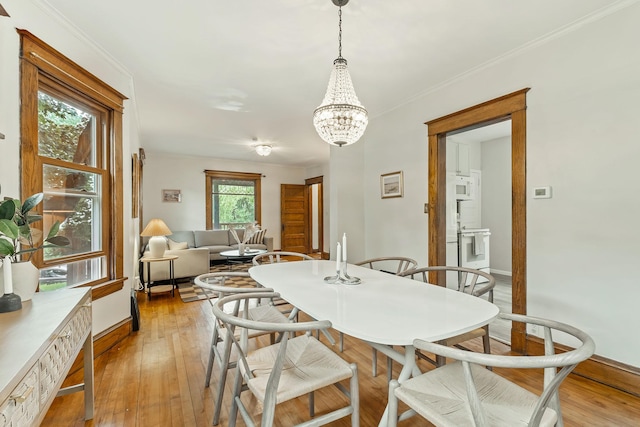 1112 29th Ave NE, Minneapolis, MN 55418 - dining room with light wood-style flooring, a chandelier, and crown molding