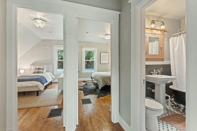 1112 29th Ave NE, Minneapolis, MN 55418 - bathroom with ensuite bathroom, hardwood / wood-style floors, and vaulted ceiling