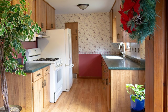 8029 2nd Ave S, Bloomington, MN 55420 - kitchen featuring wallpapered walls, white gas range, under cabinet range hood, light wood-type flooring, and dark countertops