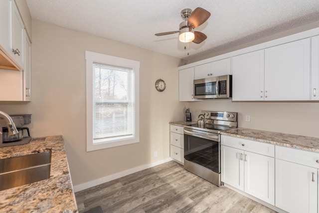 116 3rd Ave, Crosby, MN 56441 - kitchen with appliances with stainless steel finishes, light wood finished floors, ceiling fan, white cabinetry, and a textured ceiling