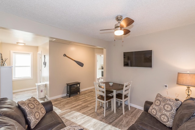 116 3rd Ave, Crosby, MN 56441 - living room with a wood stove, ceiling fan, light wood-style floors, and a textured ceiling