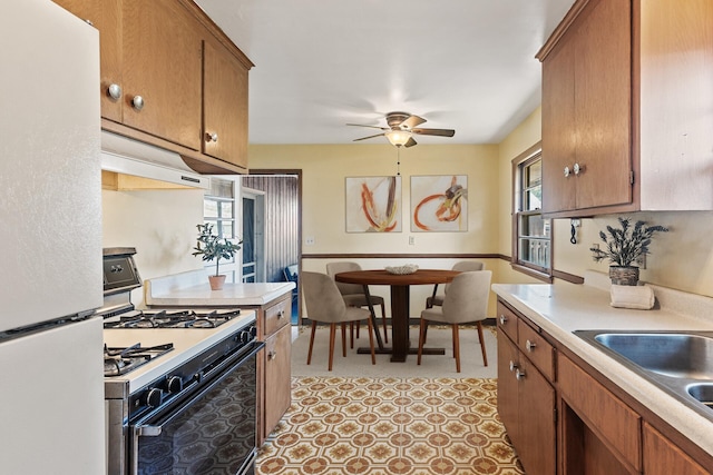 6112 Kyle Ave N, Brooklyn Center, MN 55429 - kitchen with freestanding refrigerator, range with gas stovetop, custom exhaust hood, and plenty of natural light