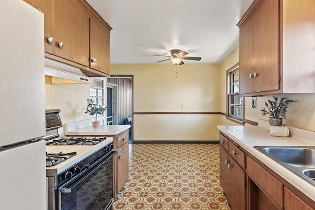 6112 Kyle Ave N, Brooklyn Center, MN 55429 - kitchen featuring freestanding refrigerator, range with gas stovetop, under cabinet range hood, ceiling fan, and light countertops