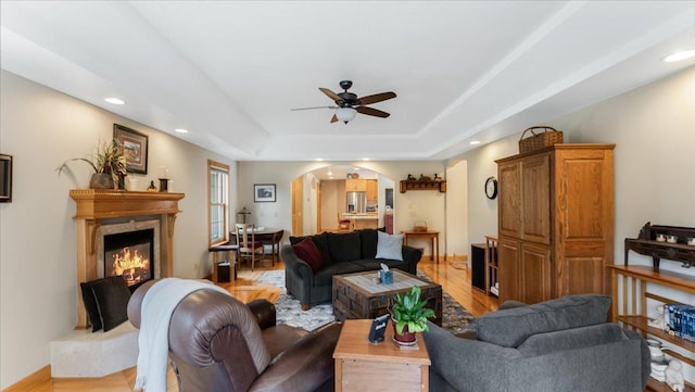 1764 State 84 SW, Pine River, MN 56474 - living room featuring arched walkways, ceiling fan, a premium fireplace, a raised ceiling, and recessed lighting