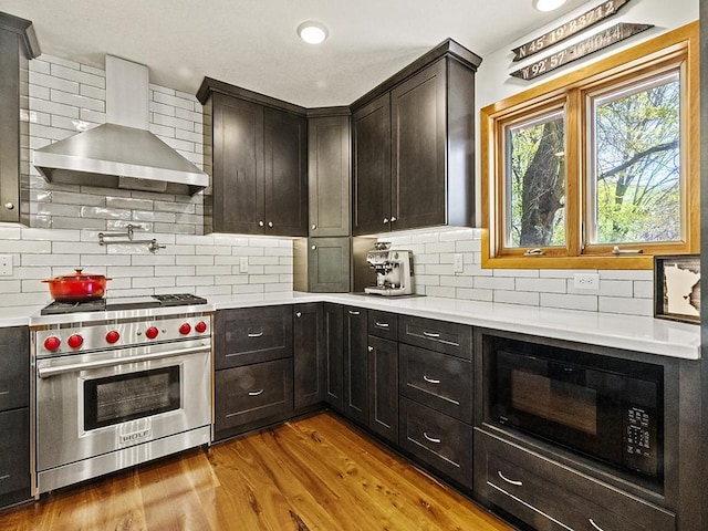 25533 Heritage Ln, Wyoming, MN 55092 - kitchen with wall chimney exhaust hood, designer stove, black microwave, backsplash, and light countertops