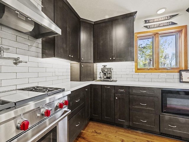 25533 Heritage Ln, Wyoming, MN 55092 - kitchen with high end stove, exhaust hood, decorative backsplash, light countertops, and wood finished floors