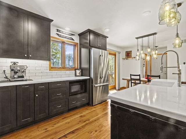 25533 Heritage Ln, Wyoming, MN 55092 - kitchen with black appliances, light wood-style flooring, light countertops, tasteful backsplash, and hanging light fixtures