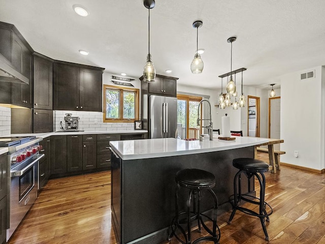 25533 Heritage Ln, Wyoming, MN 55092 - kitchen featuring high end appliances, wood finished floors, light countertops, decorative backsplash, and hanging light fixtures