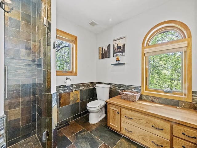25533 Heritage Ln, Wyoming, MN 55092 - bathroom featuring tile walls, plenty of natural light, a stall shower, a wainscoted wall, and stone tile flooring