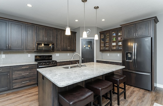 2745 Sand Trap Rd SE, Rochester, MN 55904 - kitchen with stainless steel appliances, dark brown cabinetry, light wood-type flooring, glass insert cabinets, and tasteful backsplash