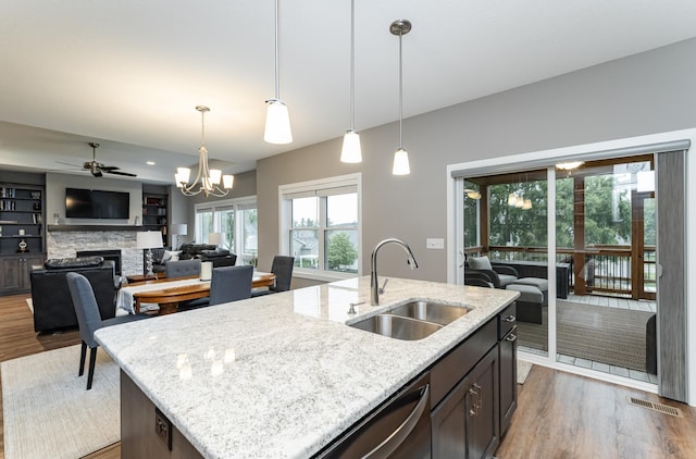2745 Sand Trap Rd SE, Rochester, MN 55904 - kitchen featuring wood finished floors, a fireplace, light stone countertops, and hanging light fixtures