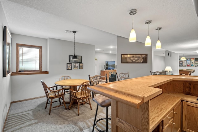 8051 Enclave Bay, Woodbury, MN 55125 - kitchen with a textured ceiling, light colored carpet, decorative light fixtures, a kitchen bar, and brown cabinets