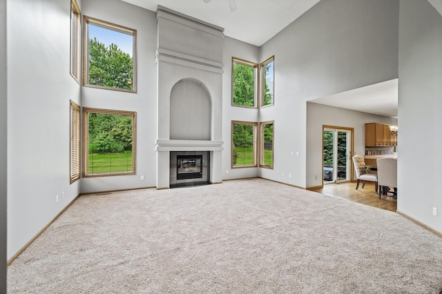 8051 Enclave Bay, Woodbury, MN 55125 - unfurnished living room with a towering ceiling, carpet, plenty of natural light, a tile fireplace, and ceiling fan