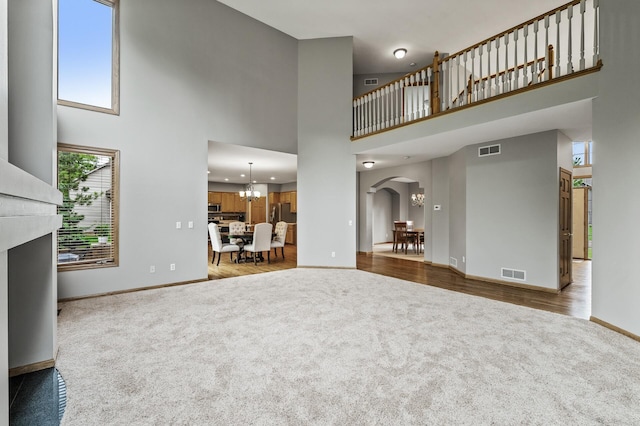 8051 Enclave Bay, Woodbury, MN 55125 - unfurnished living room with carpet floors, a high ceiling, arched walkways, and a fireplace