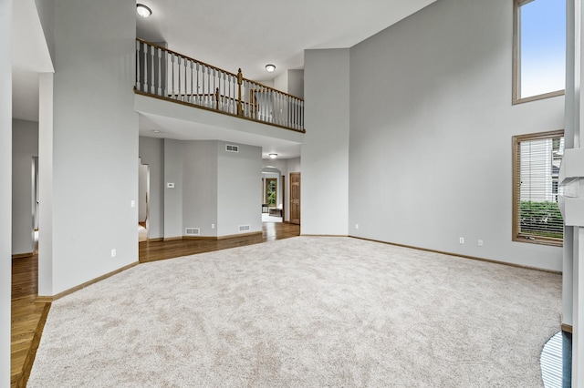 8051 Enclave Bay, Woodbury, MN 55125 - unfurnished living room featuring carpet floors, a high ceiling, wood finished floors, and arched walkways