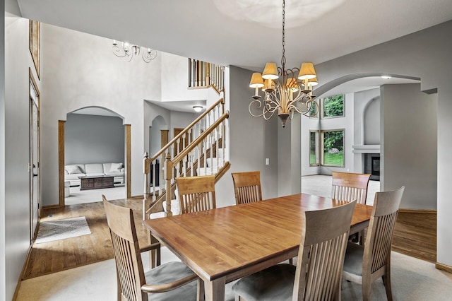 8051 Enclave Bay, Woodbury, MN 55125 - dining space featuring a chandelier, arched walkways, a high ceiling, a glass covered fireplace, and wood finished floors