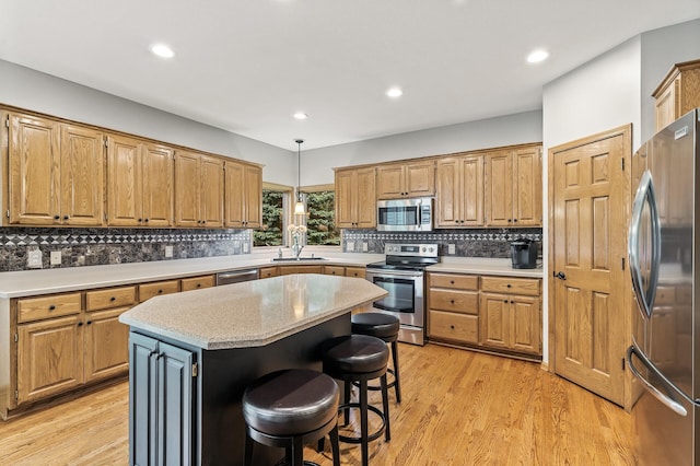 8051 Enclave Bay, Woodbury, MN 55125 - kitchen with appliances with stainless steel finishes, a kitchen island, decorative backsplash, light wood-style flooring, and a breakfast bar area