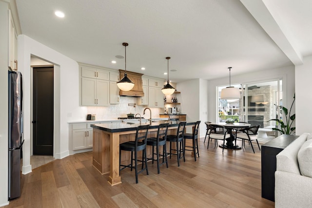 16942 47th Pl N, Plymouth, MN 55446 - kitchen featuring freestanding refrigerator, decorative backsplash, light wood finished floors, a kitchen bar, and custom exhaust hood