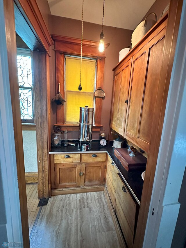 619 University Dr S, Fargo, ND 58103 - kitchen featuring dark countertops, brown cabinets, hanging light fixtures, and wood finished floors